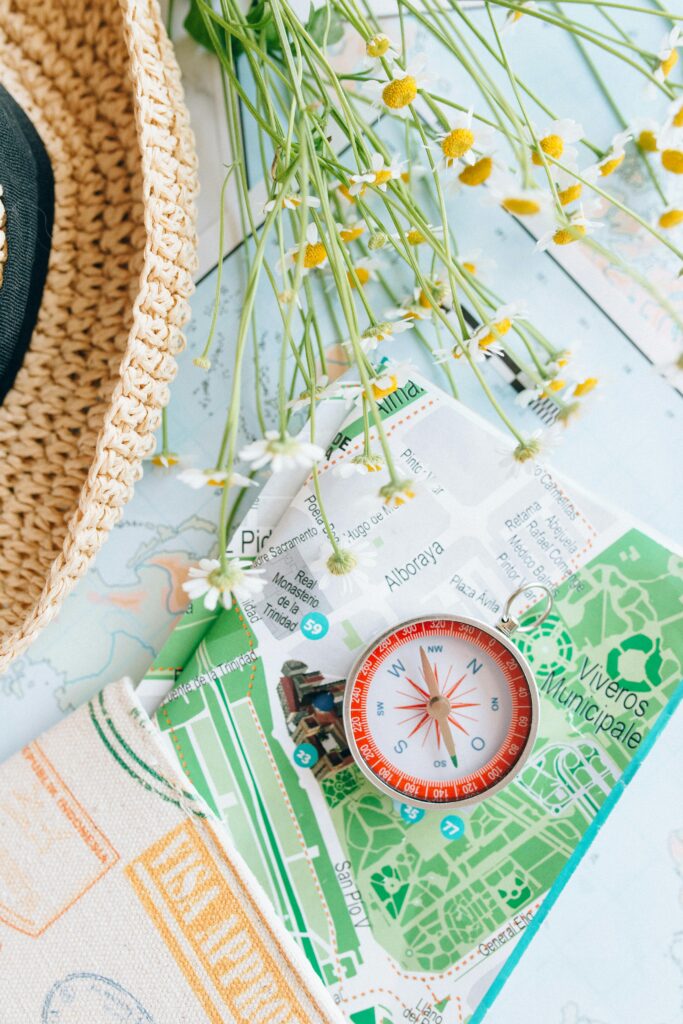 Flat lay of travel items including a map, compass, and flowers, inspiring adventure.